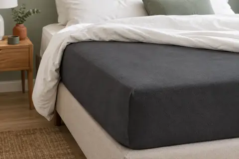 Protège-matelas imperméable anthracite ajusté sur un matelas dans une chambre épurée